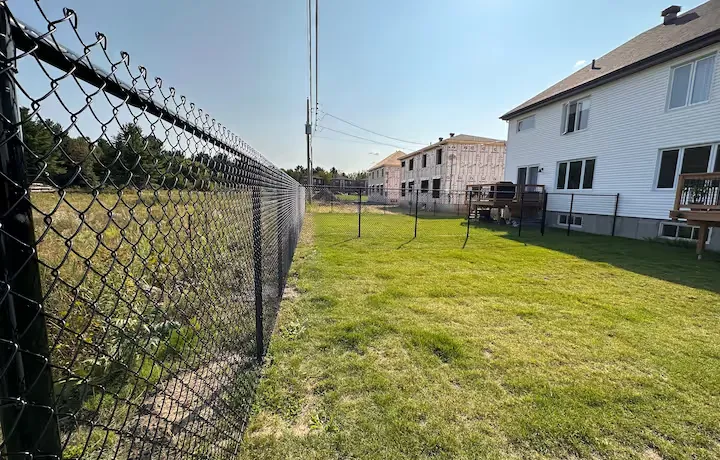 Clôture noire en métal entourant une piscine avec des fleurs rouges